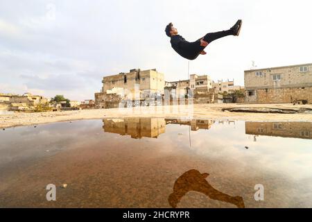 Idlib, Syrie.31st décembre 2021.Un jeune homme démontre ses compétences Parkour entre les bâtiments détruits par les frappes aériennes russes.Crédit : SOPA Images Limited/Alamy Live News Banque D'Images