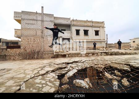 Idlib, Syrie.31st décembre 2021.Un jeune homme démontre ses compétences Parkour entre les bâtiments détruits par les frappes aériennes russes.(Photo par Omar Albam/SOPA Images/Sipa USA) crédit: SIPA USA/Alay Live News Banque D'Images