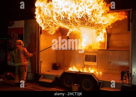 Un pompier crée une énorme boule de feu lors d'une démonstration de sécurité, illustrant ce qui se passe si de l'eau est jetée sur un feu d'huile de cuisine Banque D'Images