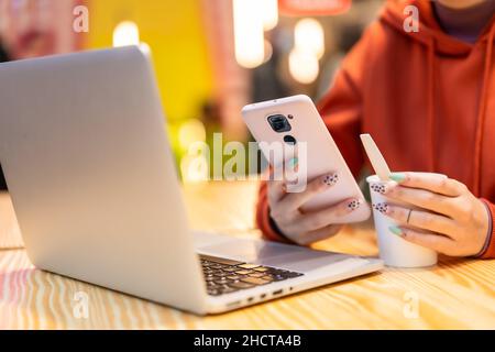 Autre personne méconnaissable avec un café chaud surfant sur Internet sur l'ordinateur et envoyant un message texte Banque D'Images