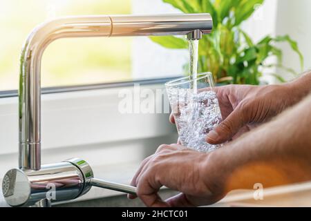 Libre tourné d'un homme de servir un verre d'eau douce dans un robinet de cuisine Banque D'Images