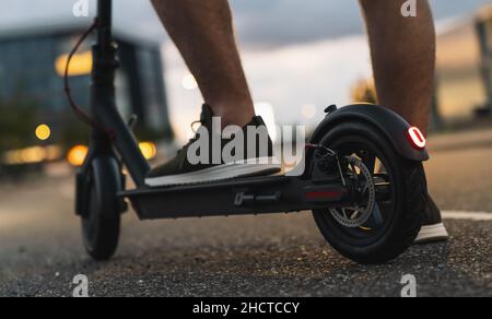 Le jeune homme est prêt à découvrir la ville de nuit avec un scooter électrique ou un e-scooter, image de concept de transport urbain électrique Banque D'Images