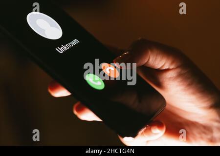 Gros plan des mains d'une femme avec un smartphone et un appel téléphonique entrant inconnu sur lui, fraude ou escroquerie Banque D'Images