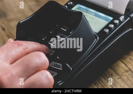 Homme saisissant à la main son mot de passe PIN lors de la commande du magasin dans le lecteur de carte Banque D'Images