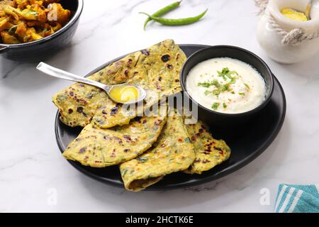 Une nourriture appelée Methi paratha ou Methi thepla est un plat de petit déjeuner indien servi avec du lait caillé et une cuillère pleine de desi ghee. Avec espace de copie. Banque D'Images