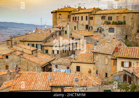 Coucher de soleil sur de vieilles maisons sur le village perché de Volterra, Italie Banque D'Images