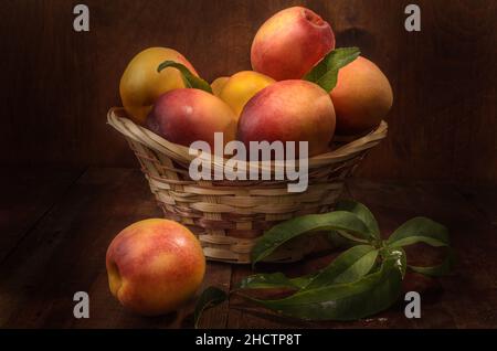 nectarines dans un panier sur fond de bois sombre dans un style rustique Banque D'Images