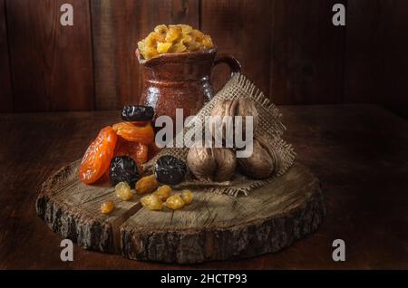 verseuse en céramique, abricots séchés et autres fruits séchés sur fond de bois foncé Banque D'Images