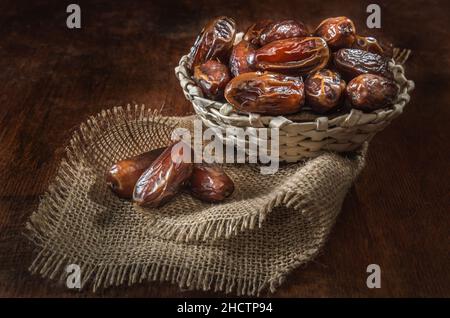 dates mûres dans un panier sur fond de bois sombre Banque D'Images