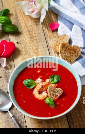 Soupe de Saint-Valentin maison, repas de fête.Soupe de tomates, purée de gazpacho avec tomates, fruits de mer servis sur une table rustique en bois.Copier l'espace. Banque D'Images
