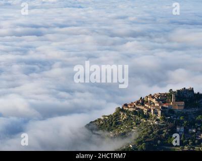 Le village médiéval de Èze au sommet d'une colline au-dessus d'une mer de nuages.Le brouillard est un phénomène météorologique très rare sur la Côte d'Azur.Alpes-Maritimes, France. Banque D'Images