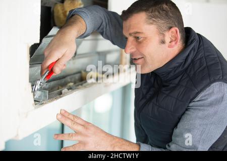 homme travaillant sur la cavité du volet roulant Banque D'Images