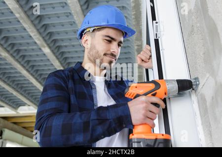 le travailleur de la construction dans un casque utilise un tournevis électrique Banque D'Images