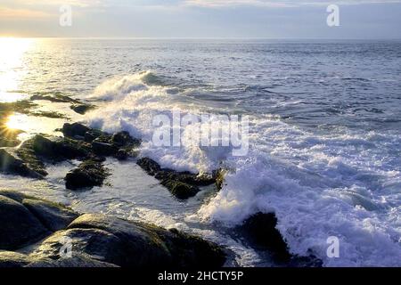 La lumière du soleil se reflète sur les vagues tandis que le soleil se couche à Halibut point dans Rockport Massachusetts. Banque D'Images