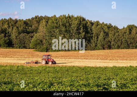 tracteur labourant un champ par temps dégagé Banque D'Images