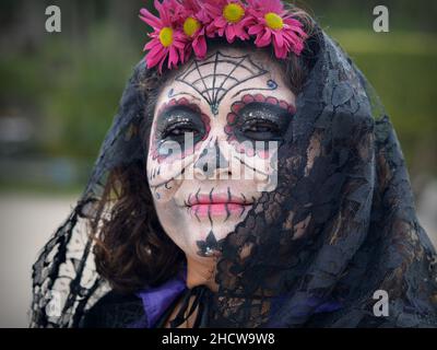 Femme mexicaine sérieuse d'âge moyen avec maquillage de visage peint zombie et foulard noir regarde le spectateur le jour des morts (Dia de los Muertos). Banque D'Images