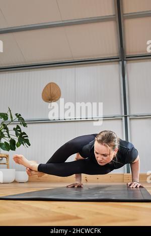 Femme athlétique faisant la posture avancée de yoga posture de Crow pose, kakasana.. Format vertical. Banque D'Images