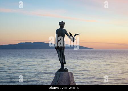 Statue de bronze Maiden avec le mouette, symbole d'Opatija en Croatie, debout sur le récif au bord de la mer Adriatique calme et regardant l'île de Cres Banque D'Images