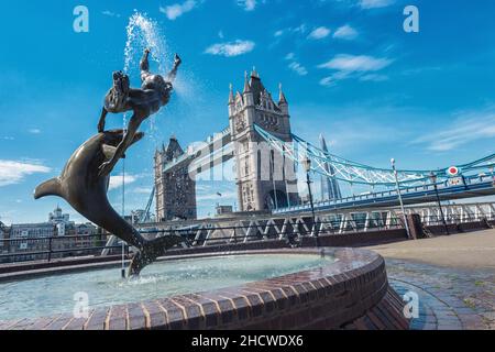 Le Tower Bridge et la statue d'une jeune fille jouant avec dauphin en St Katharine Docks de Londres. Banque D'Images