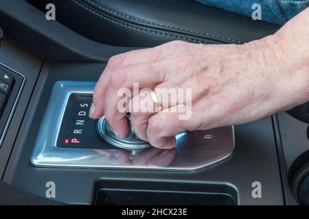 Une femme utilisant le sélecteur de vitesse dans une voiture automatique - dans ce cas, un Land Rover Discovery. Banque D'Images