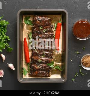 Côtes de porc cuites sur plaque de cuisson sur fond de pierre noire.Vue de dessus, plan d'appartement Banque D'Images