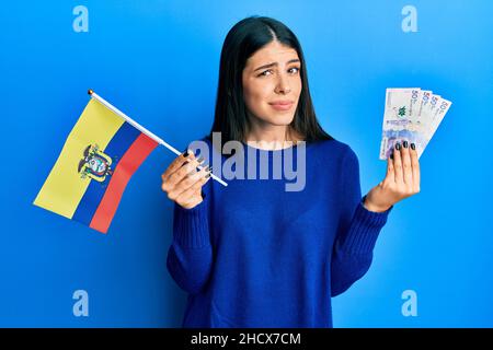 La jeune femme hispanique détient le drapeau colombien et les billets colombiens pesos expression sans indice et confuse. Notion de doute. Banque D'Images