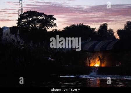 District de Mae SOT, Thaïlande.01st janvier 2022.Silhouette d'un homme Karen balayant le camping temporaire.Les Karen évacuées vivent dans un camping temporaire le long de la rivière Moei, du côté du Myanmar, qui peut être vu du côté de la Thaïlande autour du district de Mae SOT.Ils vivent ici depuis environ 3 semaines après le conflit entre l'armée du Myanmar et l'armée KNU (Union nationale Karen) dans l'État Karen du Myanmar.Crédit : SOPA Images Limited/Alamy Live News Banque D'Images