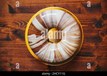 Mousse ronde avec glaçage en marbre sur une assiette dorée sur la table.Vue de dessus Banque D'Images