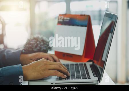 homme d'affaires est en train de taper dans les recherches d'informations d'affaires sur internet à un ordinateur portable à son bureau. Banque D'Images