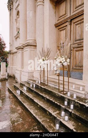 Des bouquets de fleurs se tiennent sur des piédestaux dorés en métal sur les marches de l'église Banque D'Images