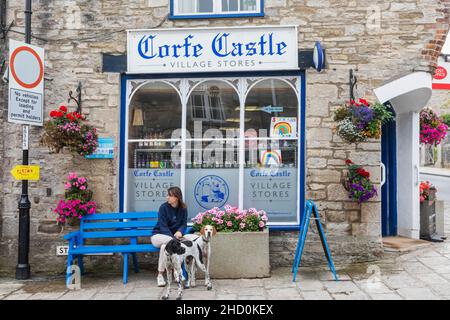 Angleterre, Dorset, île de Purbeck, Corfe Castle Village, femme et chiens devant les magasins de Corfe Castle Village Banque D'Images