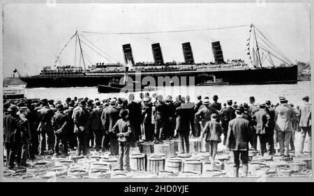 RMS Lusitania, New York, septembre 1907, l'arrière-Vue de côté, au cours de voyage, avec une grande foule d'hommes, en premier plan, debout sur des tonneaux Banque D'Images