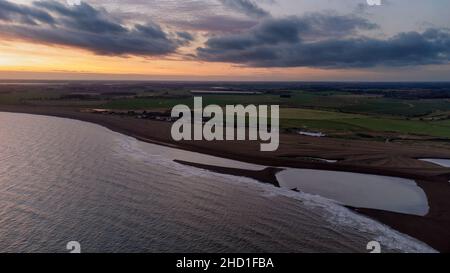 Une vue aérienne du coucher du soleil sur la côte à Shingle Street dans Suffolk, Royaume-Uni Banque D'Images