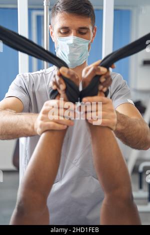 Médecin spécialisé réhabilitant les bras de son patient à l'aide d'un équipement de gym Banque D'Images