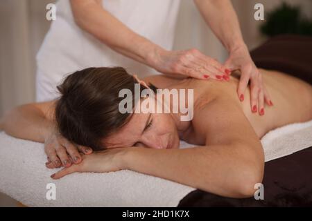 Femme adulte bénéficiant d'un massage relaxant du dos au centre de spa Banque D'Images