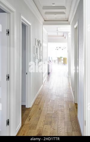 Long couloir lumineux avec murs blancs et sol propre recouvert d'élégant parquet en chêne dans l'élégant appartement rénové