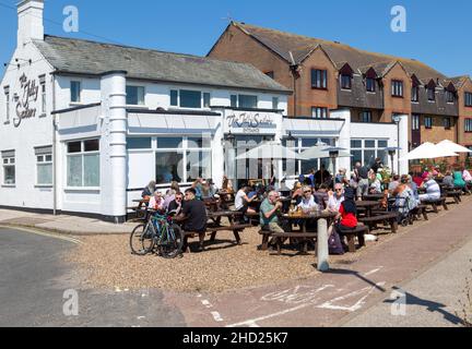 Les gens assis au soleil à l'extérieur du pub Jolly marins, Pakefield, Lowestoft, Suffolk, Angleterre,ROYAUME-UNI Banque D'Images