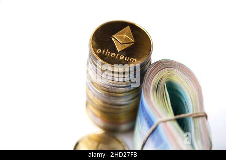 Rouler les billets israéliens Shekel ils près des jetons crypto-monnaies Ethereum eth, vu d'en haut, sur fond blanc.Mise au point sélective. Avec espace pour le placement du texte.Isolé .Photo de haute qualité Banque D'Images