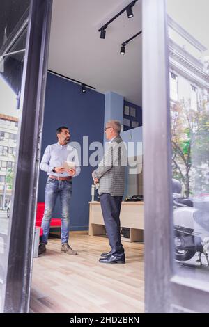 Deux hommes d'affaires principaux parlent des nouveaux plans, par le biais de la fenêtre Banque D'Images