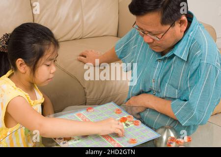 Famille américaine vietnamienne à la maison, fille de 8 ans jouant au jeu de société vietnamien avec son père (cờ tướng échecs chinois) Banque D'Images