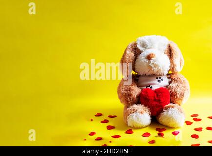 poupée de chien blanche et brune avec coeur rouge sur fond jaune.un symbole de l'amour.Saint Valentin Banque D'Images