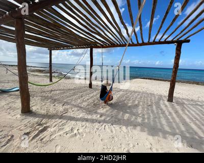 Femme avec un chapeau se détendant dans un hamac sur une plage tropicale à Riviera Maya, Mexique.Concept vacances d'été. Banque D'Images