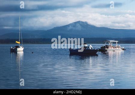 Bateaux de plaisance à l'ancre dans le lac Jackson au parc national de Grand Teton alors que l'aube se brise sur une matinée nuageux. Banque D'Images