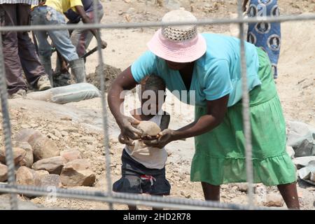 On voit une femme aider son enfant à porter une pierre lors de la construction d'un déversoir dans le district de Binga.Beaucoup de femmes travaillent sur des projets avec leurs enfants car elles n'ont pas de baby-minders.Zimbabwe. Banque D'Images