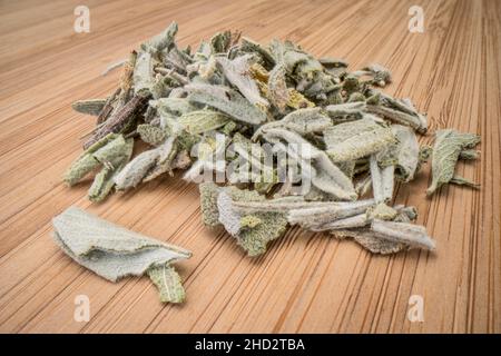 feuilles en vrac de thé sec aux herbes de sauge, gros plan d'une pile sur un panneau de bambou Banque D'Images