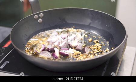 Cuisson des légumes au wok.Attache.Chef friture de l'oignon blanc haché.Hachée dans une poêle.Cuisson à la vapeur à partir de la poêle avec l'oignon.Légumes Banque D'Images