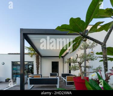 Patio extérieur tendance pergola structure d'ombre, auvent et toit de patio, salon de jardin, chaises, grill en métal entouré par l'aménagement paysager Banque D'Images