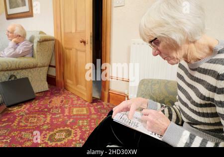 Femme âgée qui garde l'esprit actif en faisant des mots croisés puzzle Banque D'Images