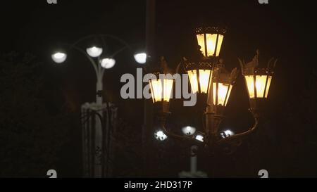 Deux lanternes de rue différentes sur fond de ciel noir.Lampes de rue modernes et démodées avec des lumières jaunes et blanches dans la rue de la ville la nuit. Banque D'Images