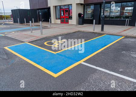 Symbole international pour personnes handicapées peint en jaune vif sur une place de parking du centre commercial. Banque D'Images
